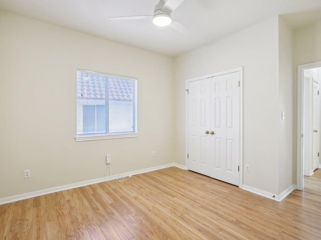 unfurnished bedroom featuring light wood finished floors, a closet, a ceiling fan, and baseboards