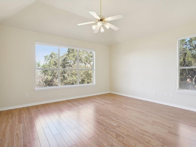 empty room with baseboards, ceiling fan, vaulted ceiling, and light wood-style floors