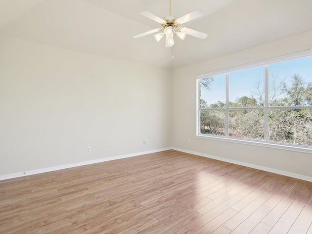 empty room with baseboards, vaulted ceiling, a ceiling fan, and light wood-style floors