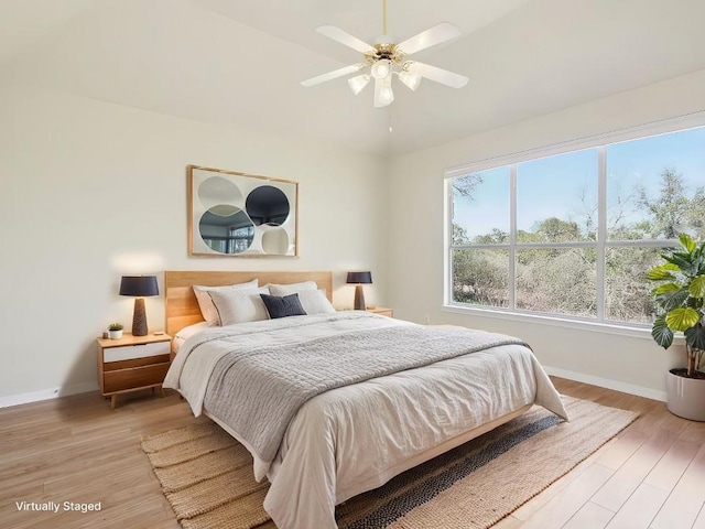 bedroom with ceiling fan, light wood-style flooring, and baseboards