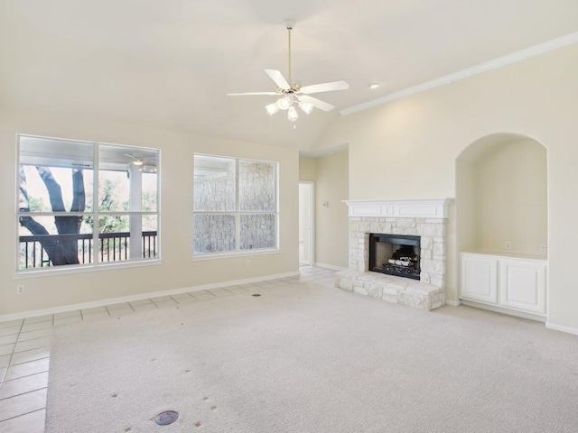 unfurnished living room featuring lofted ceiling, a stone fireplace, carpet floors, a ceiling fan, and baseboards