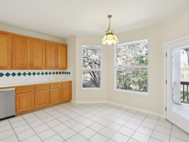 kitchen featuring plenty of natural light, hanging light fixtures, light countertops, stainless steel dishwasher, and backsplash