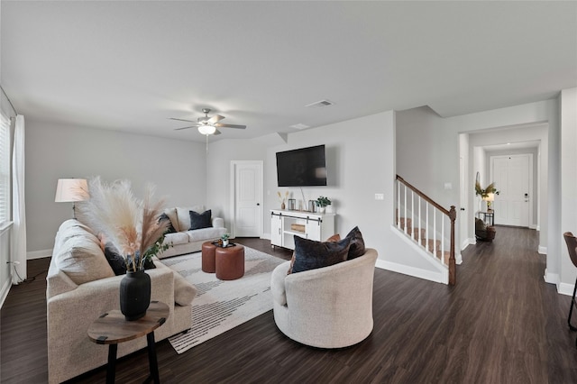 living area with dark wood-type flooring, visible vents, baseboards, and stairs