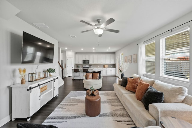 living area with stairway, visible vents, and dark wood finished floors