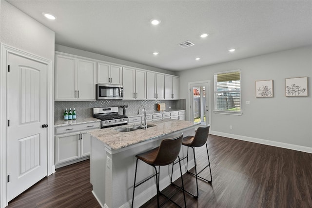 kitchen featuring stainless steel appliances, a sink, visible vents, and decorative backsplash