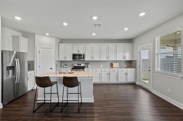 kitchen featuring visible vents, dark wood-style flooring, stainless steel appliances, white cabinetry, and a sink