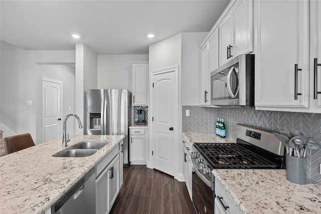 kitchen featuring decorative backsplash, dark wood finished floors, stainless steel appliances, white cabinetry, and a sink