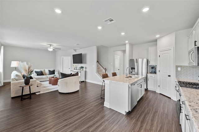 kitchen with dark wood-style flooring, stainless steel appliances, tasteful backsplash, open floor plan, and white cabinetry