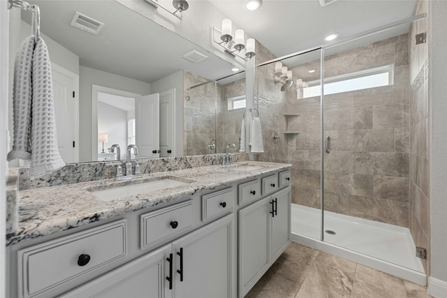 bathroom with a stall shower, visible vents, and a sink