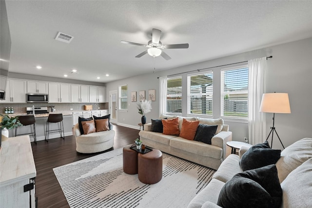 living room featuring recessed lighting, visible vents, dark wood-type flooring, a ceiling fan, and baseboards