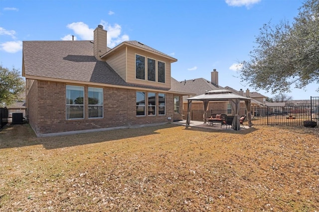 back of house with brick siding, fence, a gazebo, a chimney, and a patio area