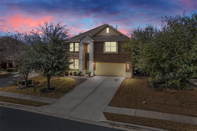 view of front of property featuring an attached garage, stone siding, concrete driveway, and brick siding