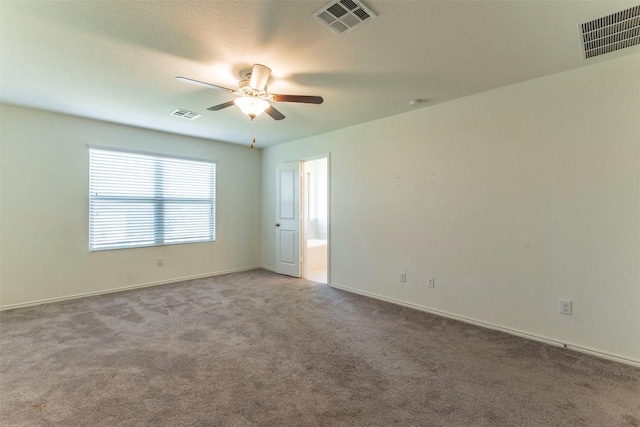 empty room with carpet, visible vents, and ceiling fan