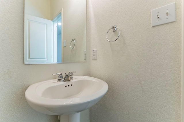 bathroom featuring a sink and a textured wall