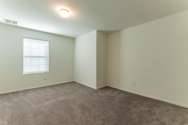 spare room featuring carpet, visible vents, and baseboards