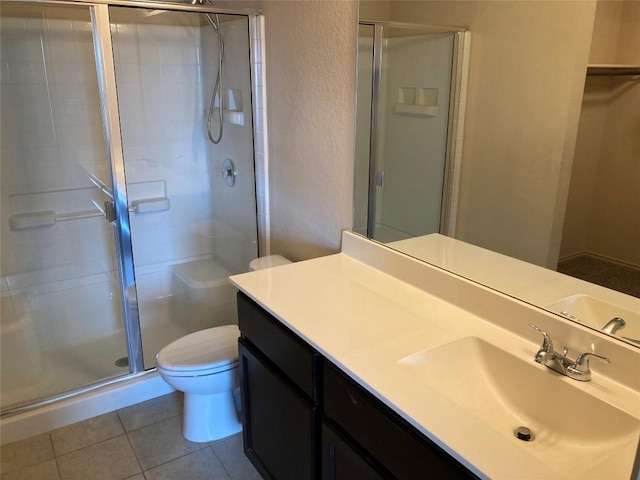 bathroom featuring a textured wall, toilet, vanity, tile patterned floors, and a stall shower