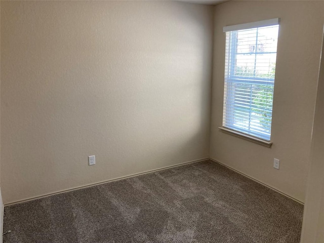 empty room featuring a healthy amount of sunlight and dark carpet