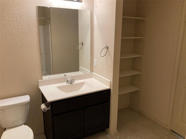 bathroom with toilet, a textured wall, and vanity