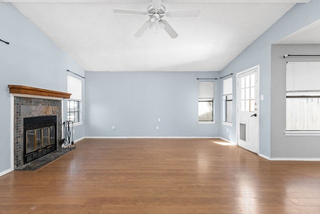 unfurnished living room featuring vaulted ceiling, ceiling fan, a fireplace, and wood finished floors