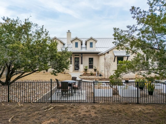 rear view of house with a standing seam roof, fence, metal roof, and a patio