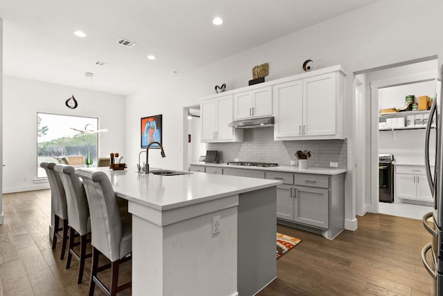 kitchen with visible vents, range, a sink, under cabinet range hood, and backsplash