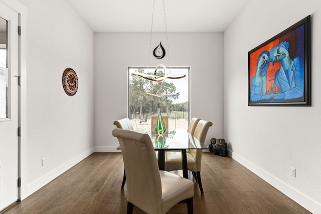 dining space featuring dark wood-type flooring, an inviting chandelier, and baseboards