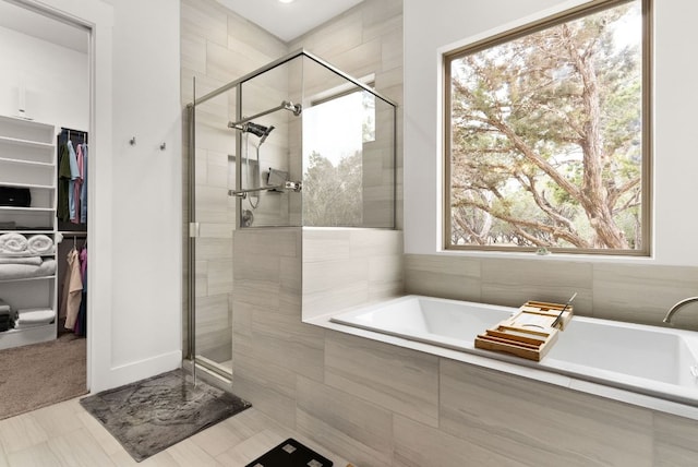 bathroom with a garden tub, a shower stall, and a walk in closet