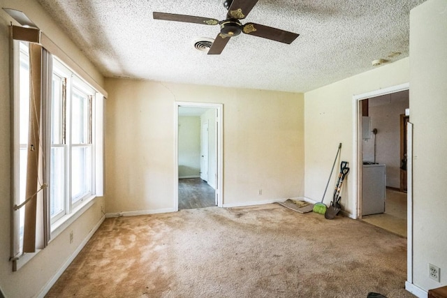 unfurnished room with a textured ceiling, washer / clothes dryer, carpet, and visible vents