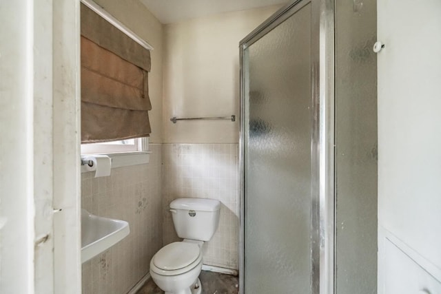 full bath with wainscoting, a shower stall, toilet, and tile walls