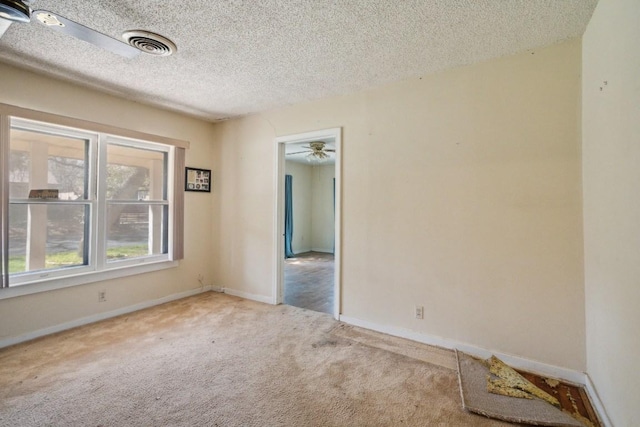 spare room with baseboards, visible vents, ceiling fan, a textured ceiling, and carpet floors