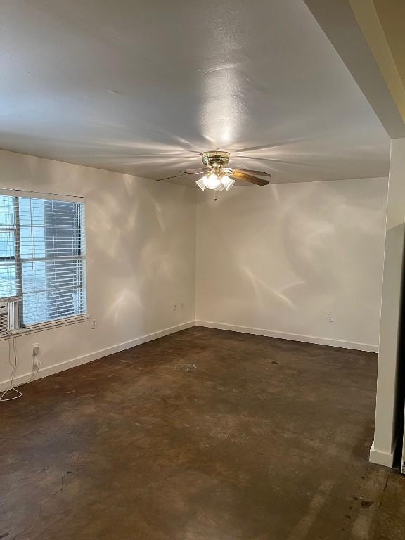 spare room with a ceiling fan, baseboards, and concrete flooring