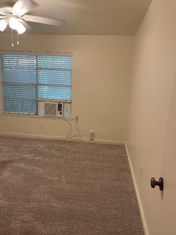 carpeted spare room with ceiling fan, baseboards, and cooling unit