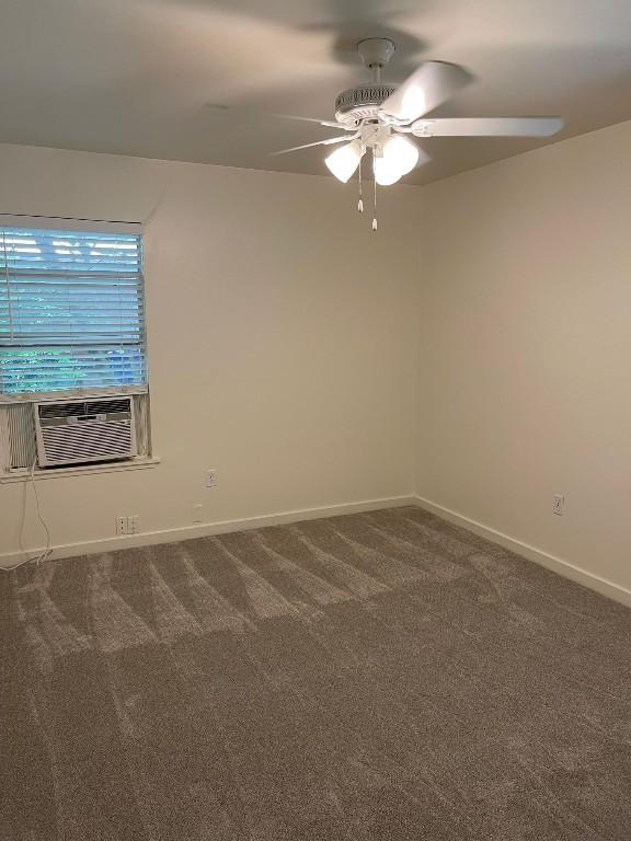 empty room with a ceiling fan, cooling unit, dark carpet, and baseboards