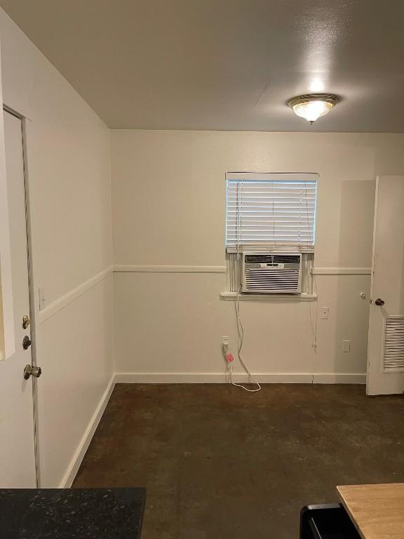 spare room featuring concrete floors, baseboards, and cooling unit