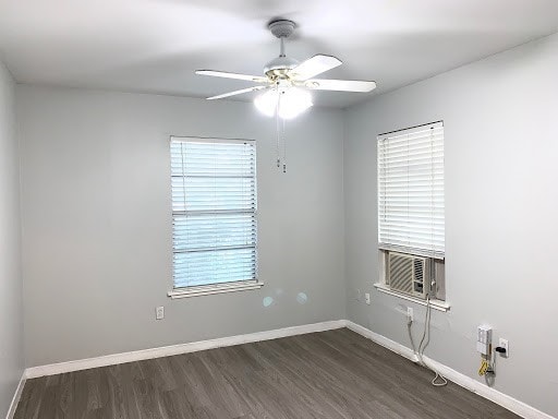 empty room with dark wood finished floors, baseboards, and ceiling fan