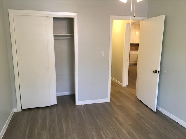 unfurnished bedroom with a closet, dark wood finished floors, and baseboards