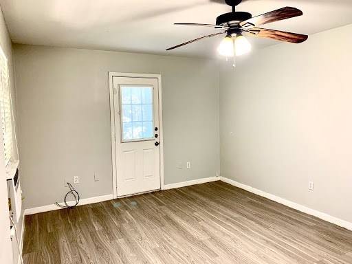 spare room featuring wood finished floors, a ceiling fan, and baseboards