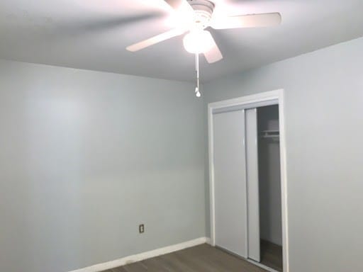 unfurnished bedroom with ceiling fan, baseboards, dark wood finished floors, and a closet