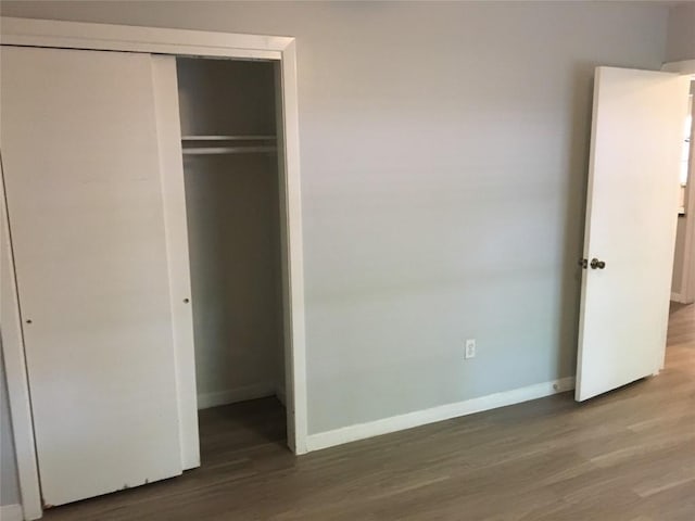 unfurnished bedroom featuring a closet, baseboards, and wood finished floors