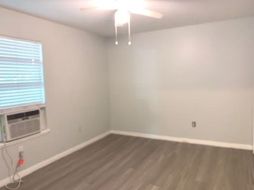 spare room with cooling unit, baseboards, and wood finished floors