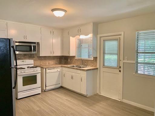 kitchen featuring white appliances, white cabinetry, and a sink