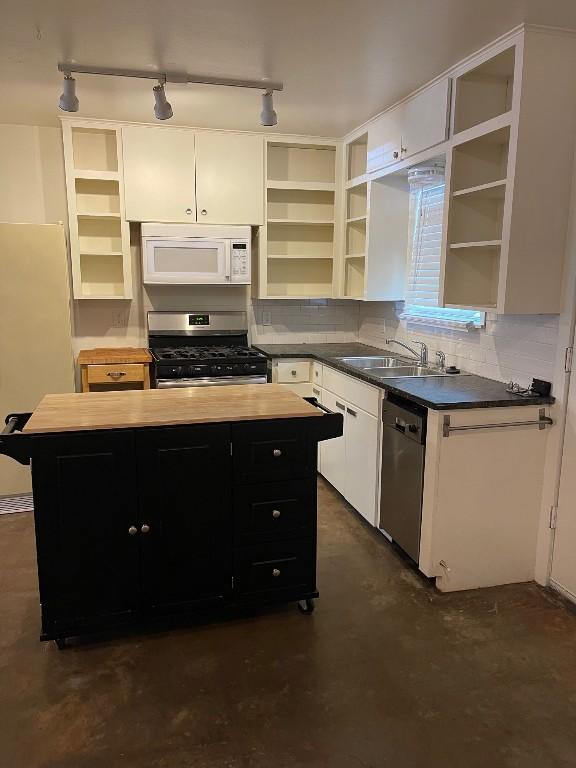 kitchen with stainless steel appliances, open shelves, and dark cabinets