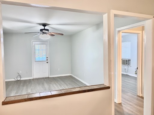 foyer entrance featuring ceiling fan, baseboards, and wood finished floors