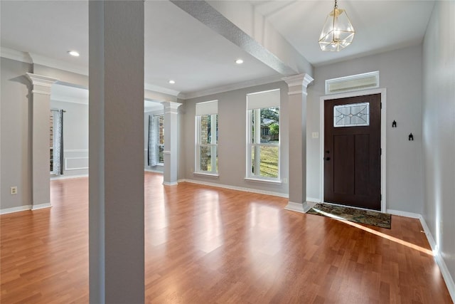 foyer featuring ornamental molding, ornate columns, and wood finished floors