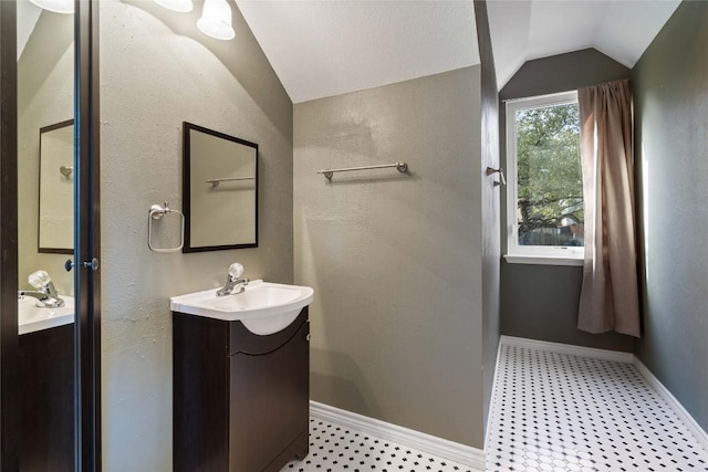 bathroom with vaulted ceiling, vanity, and baseboards