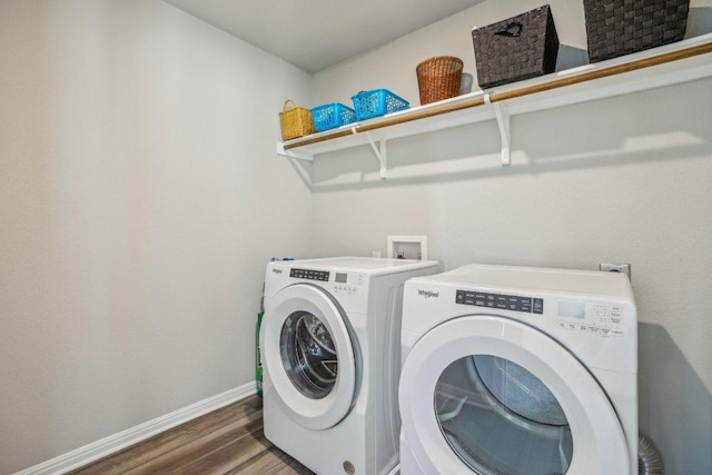 clothes washing area featuring washer and dryer, baseboards, wood finished floors, and laundry area