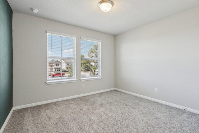 carpeted empty room featuring baseboards