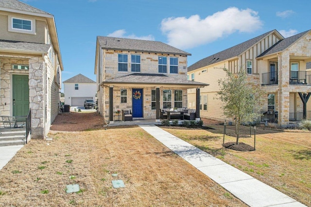 view of front facade featuring stone siding, covered porch, and a front yard