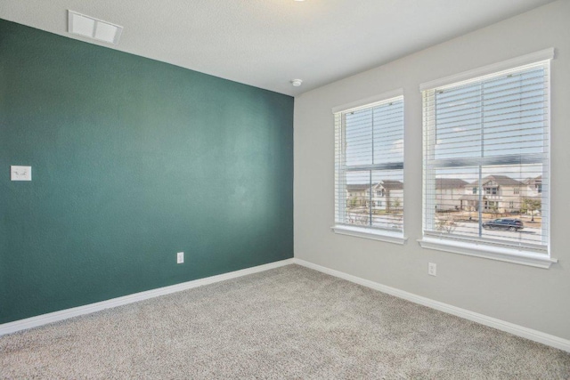 carpeted spare room featuring baseboards and visible vents