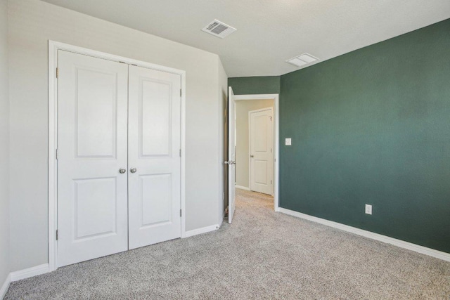 unfurnished bedroom with carpet flooring, baseboards, visible vents, and a closet